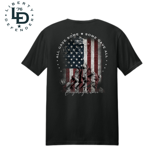 Patriotic Memorial Day t-shirt design featuring battle ground flag raising, American flag, and 'All Gave Some, Some Gave All' slogan – Liberty Defender brand, perfect for veterans and patriots in Texas, Florida, Ohio, and all across the USA.