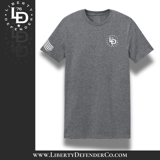 Front view of heather gray Liberty Defender t-shirt with small circular Liberty Defender logo on the left chest and American flag graphic on the sleeve